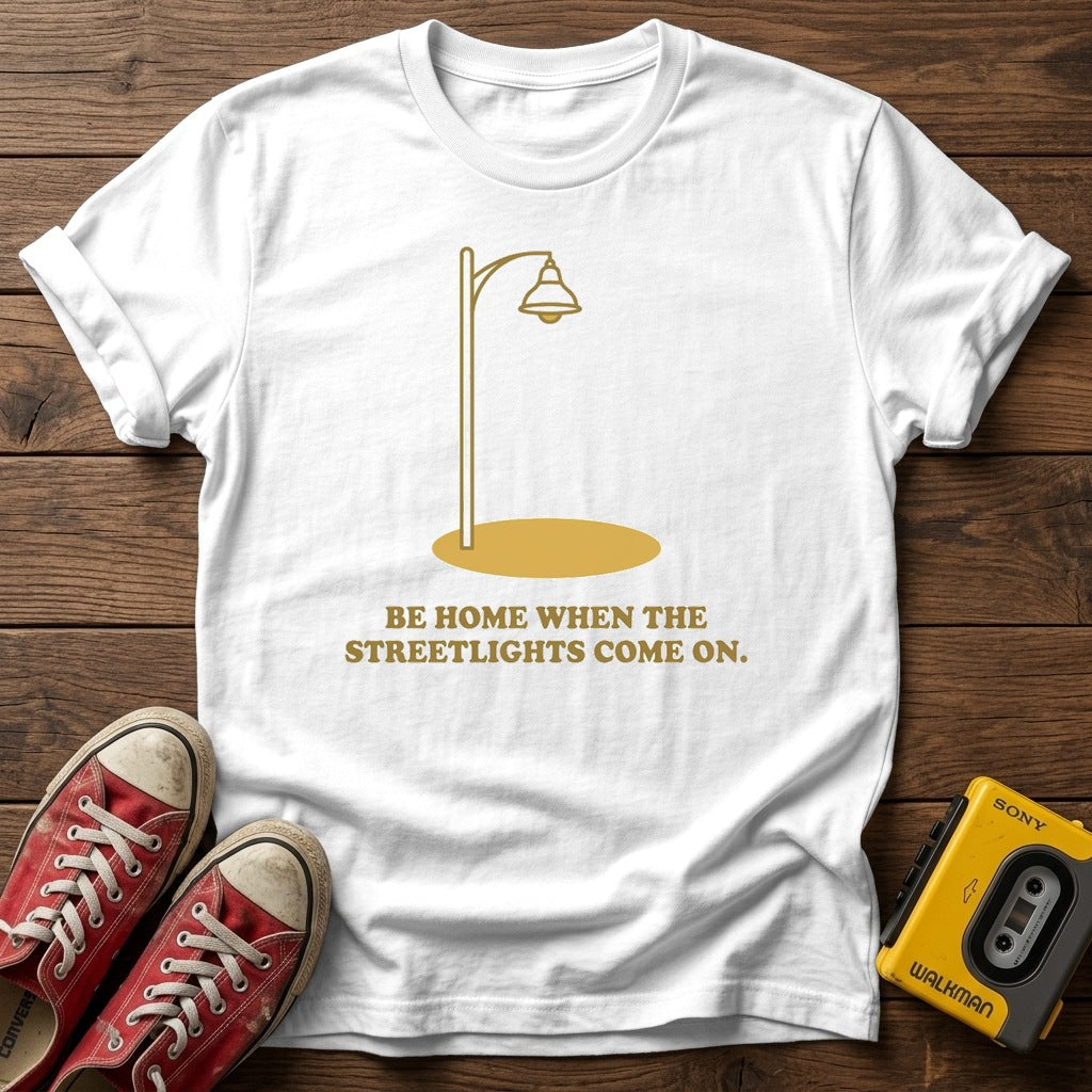“Be Home When the Streetlights Come On”  T‑Shirt — White wood flat-lay