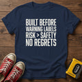 “Built Before Warnings Labels Risk + Safety No Regrets” Graphic T-Shirt — Navy wood flat-lay