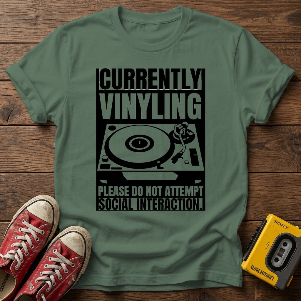 "Currently Vinyling, Please Do Not Attempt Social Interaction" T-Shirt — Military Green wood flat-lay