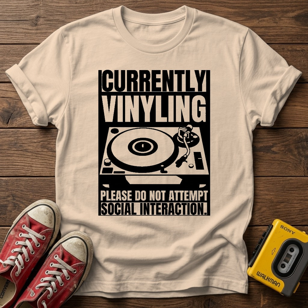"Currently Vinyling, Please Do Not Attempt Social Interaction" T-Shirt — Natural wood flat-lay