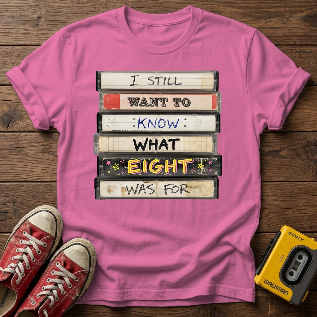 “I Still Want To Know What Eight Was For” Retro VHS Stack T Shirt — Azalea wood flat-lay