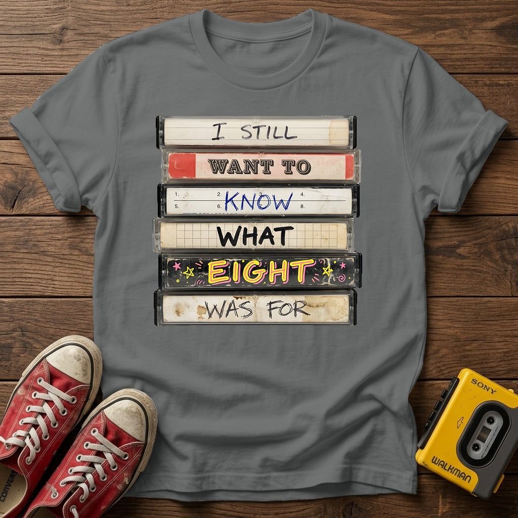 “I Still Want To Know What Eight Was For” Retro VHS Stack T Shirt — Graphite Heather wood flat-lay