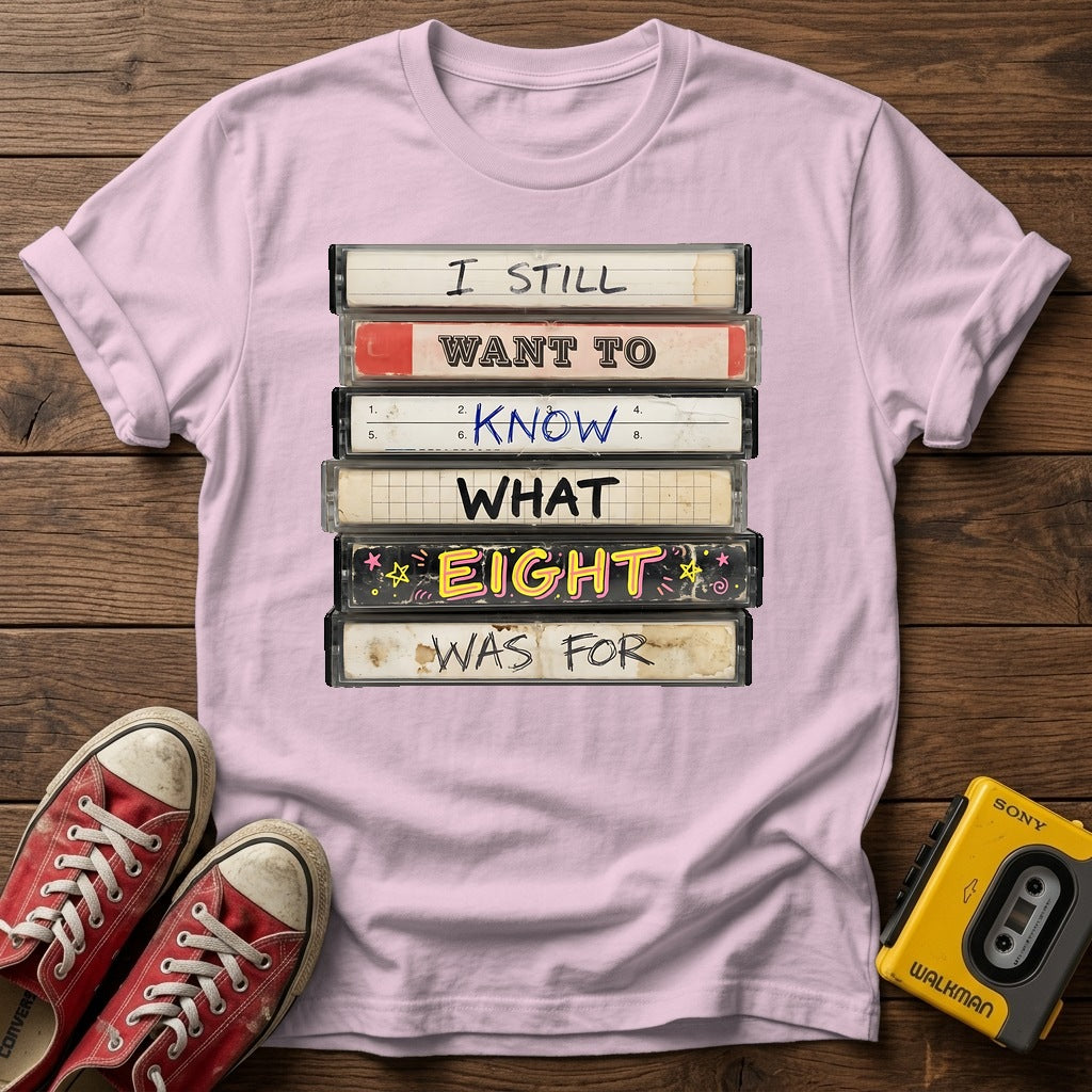 “I Still Want To Know What Eight Was For” Retro VHS Stack T Shirt — Light Pink wood flat-lay