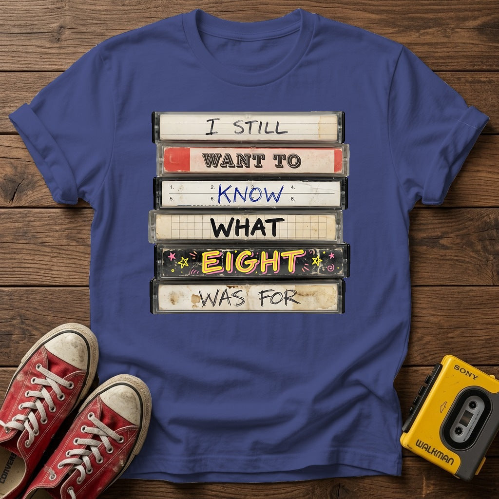 “I Still Want To Know What Eight Was For” Retro VHS Stack T Shirt — Metro Blue wood flat-lay