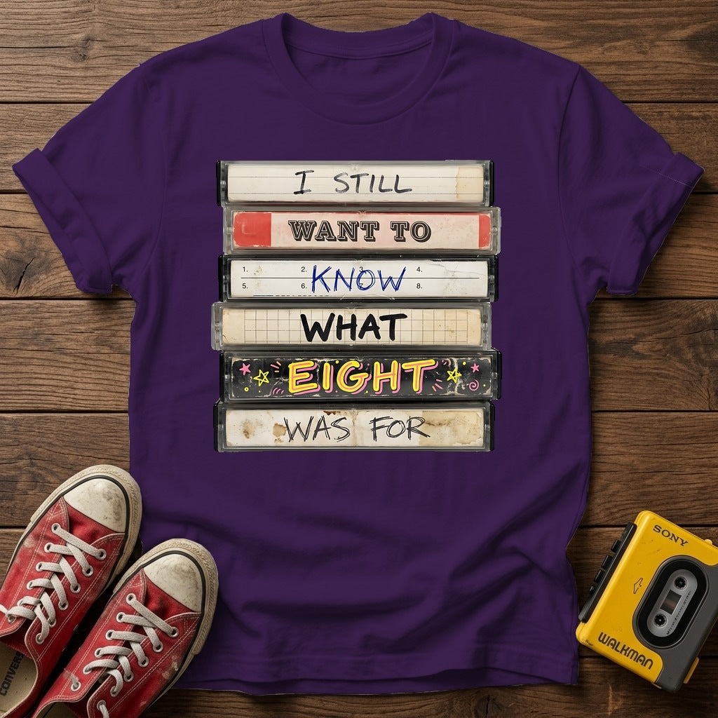 “I Still Want To Know What Eight Was For” Retro VHS Stack T Shirt — Purple wood flat-lay