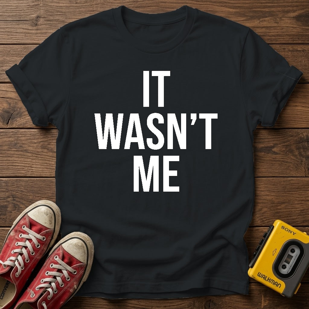 It Wasn't Me T-Shirt — Black wood flat-lay