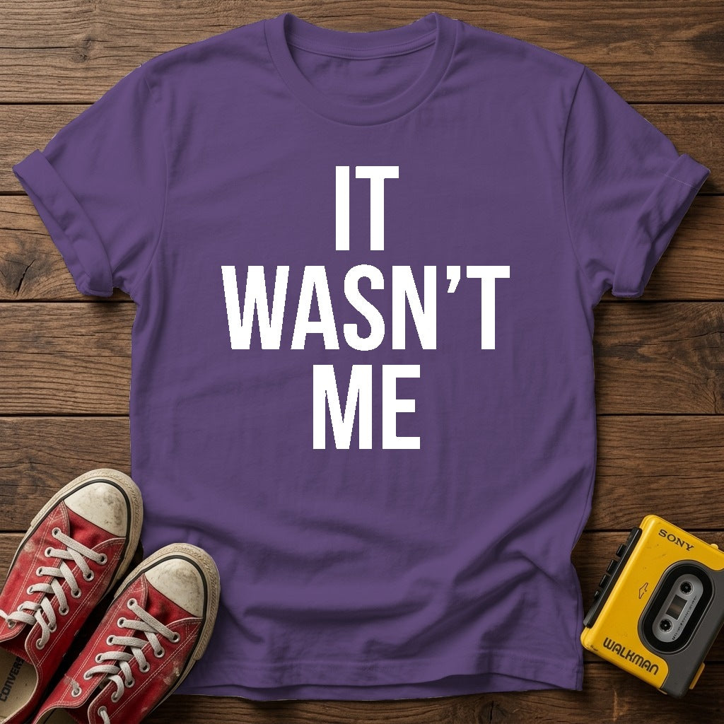 It Wasn't Me T-Shirt — Heather Purple wood flat-lay