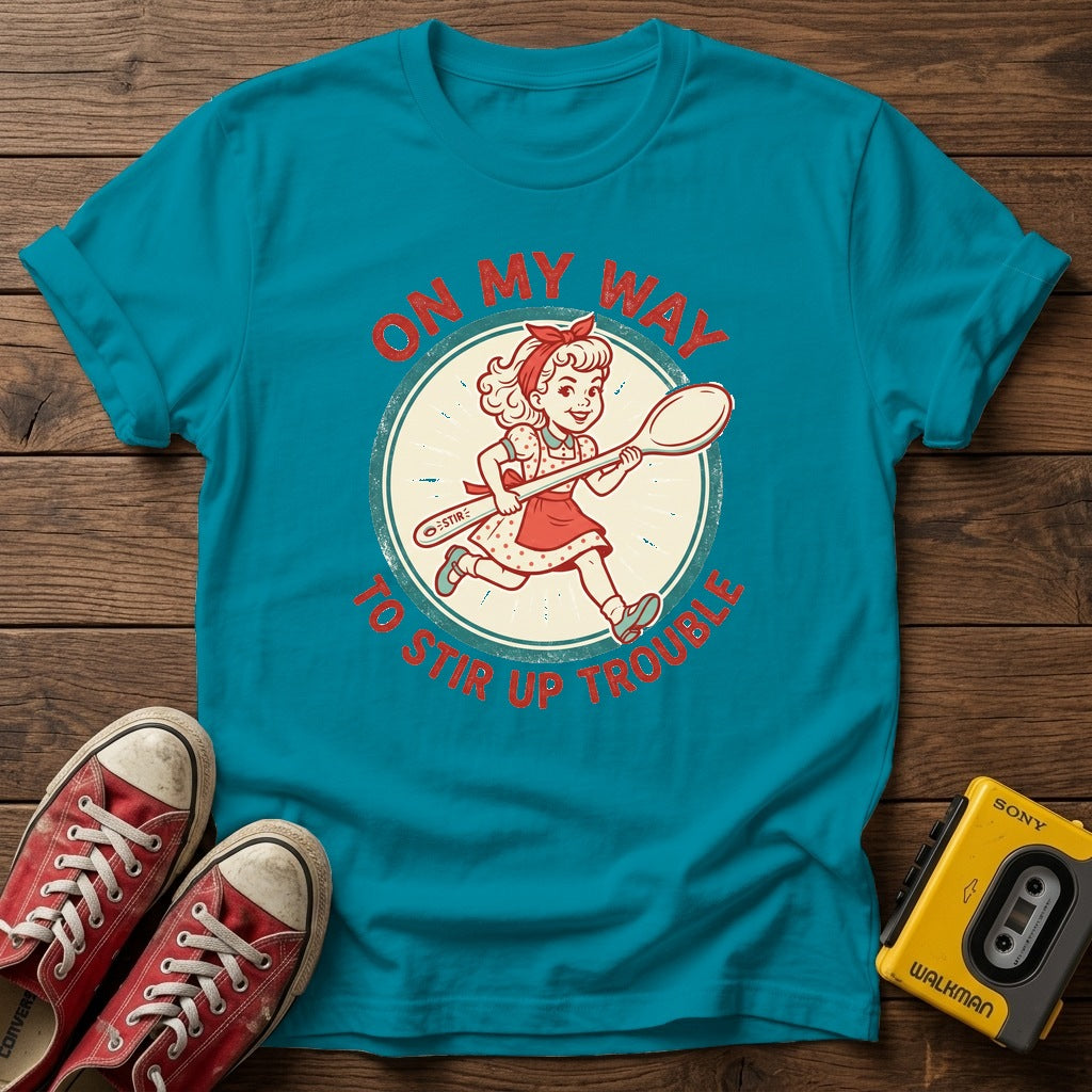 "On My Way to Stir Up Trouble" T-Shirt — Tropical Blue wood flat-lay